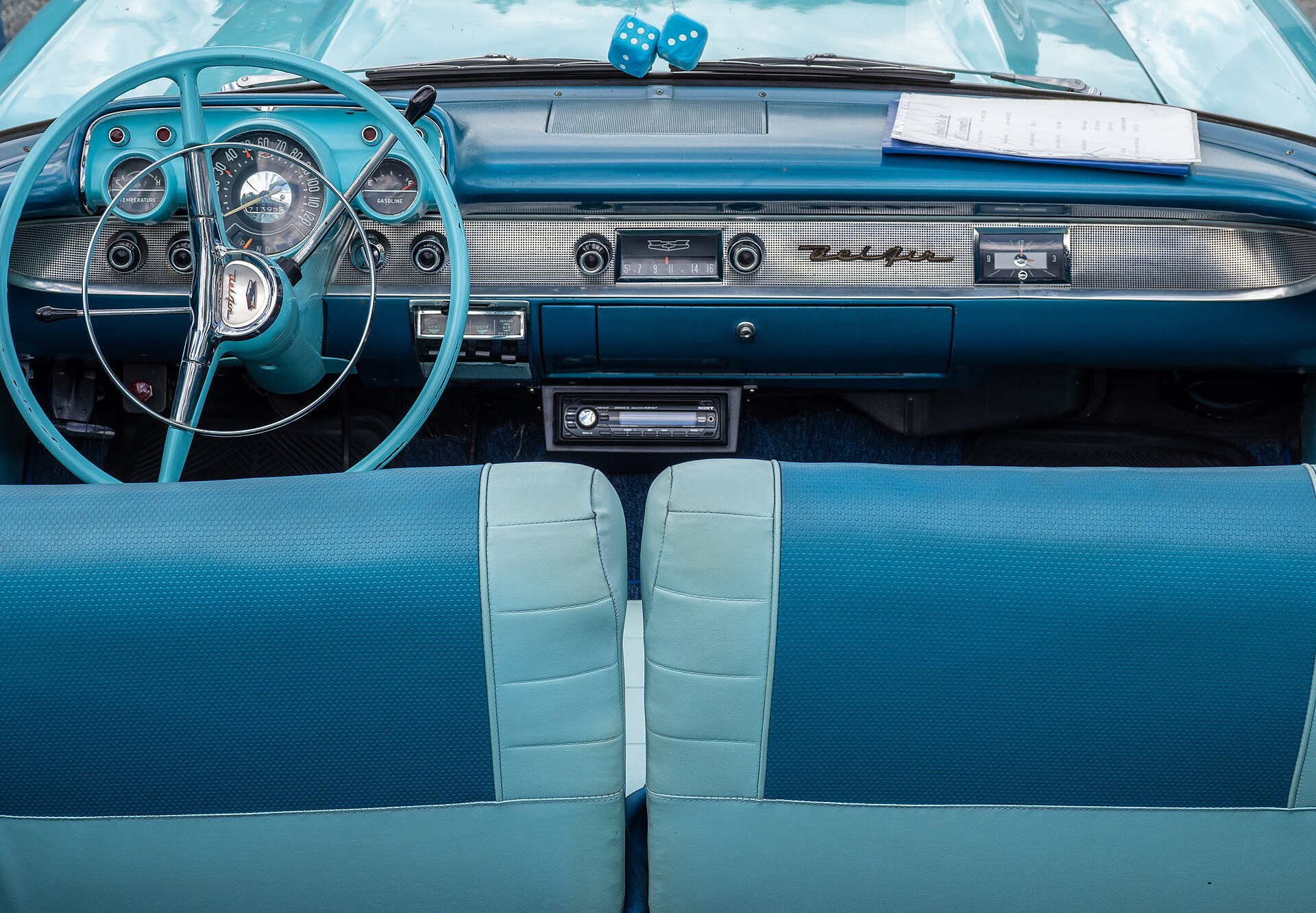 A blue 1957 Bel Air dashboard with the steering wheel, full instrument panel, and Bel Air script visible.