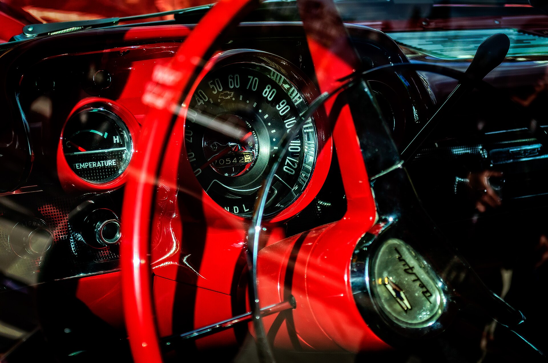 A close view of a 1957 Chevrolet instrument cluster through the steering wheel.