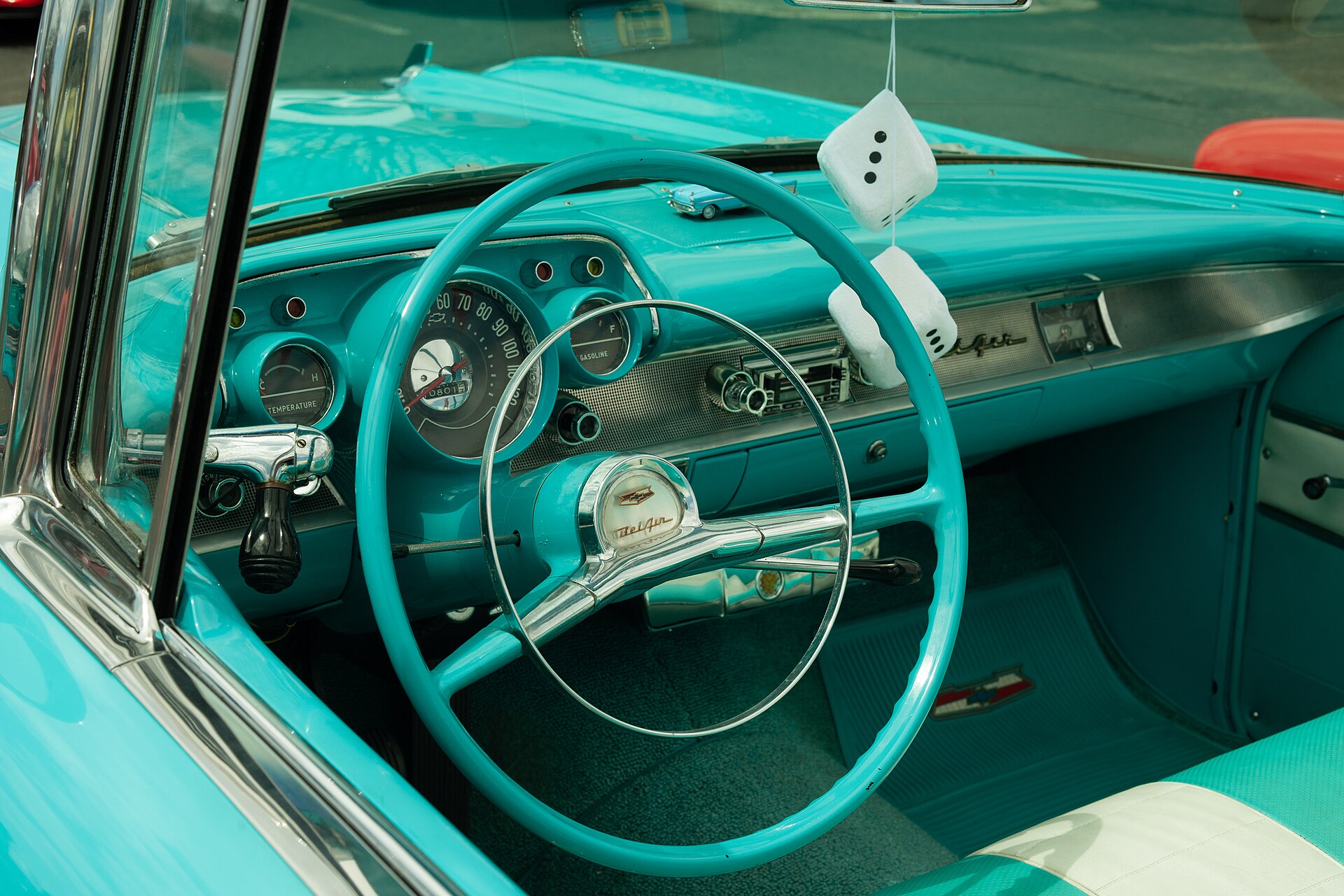 A turquoise 1957 Chevrolet cabin, steering wheel, dashboard, and front bench seat.