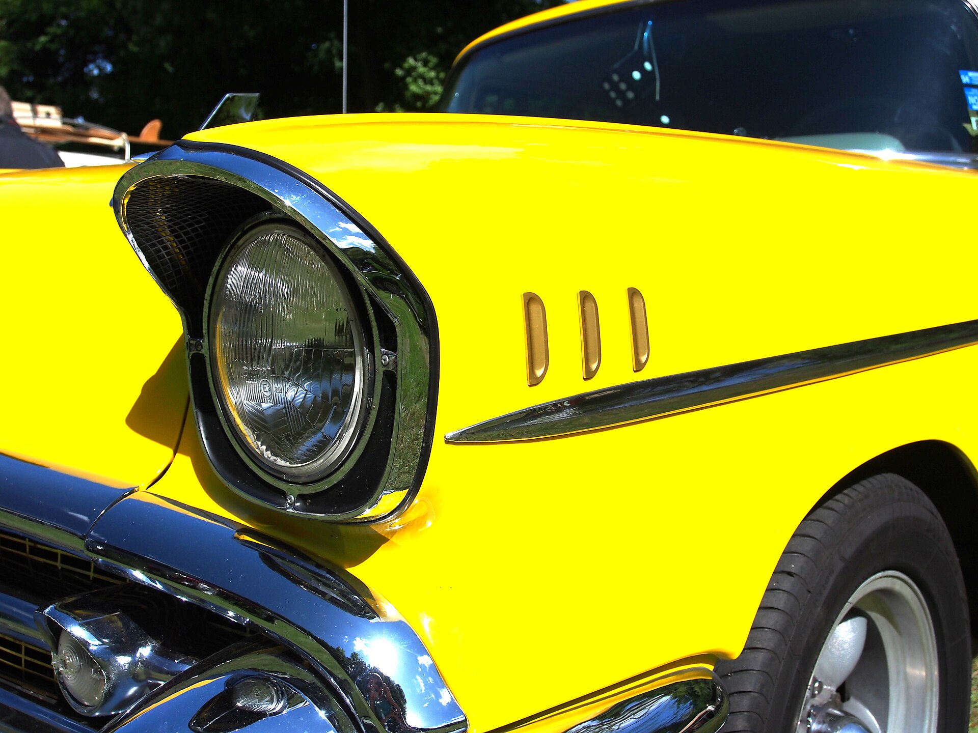 A 1957 Bel Air headlamp surround with upper mesh and three fender louvers.