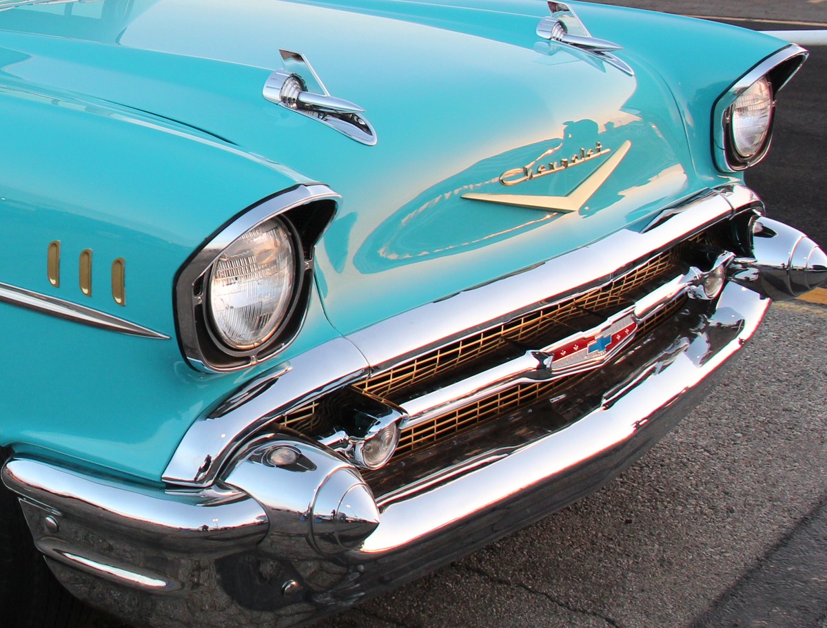 Detail crop of the cover photograph: twin hood ornaments, headlamp surrounds, V emblem and grille.